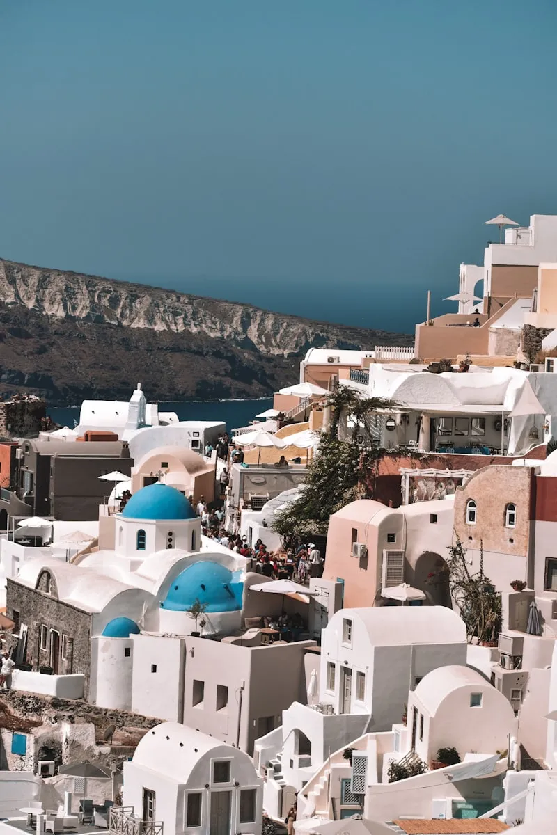 Aerial view of white buildings and blue domes in Santorini Greece overlooking Aegean Sea